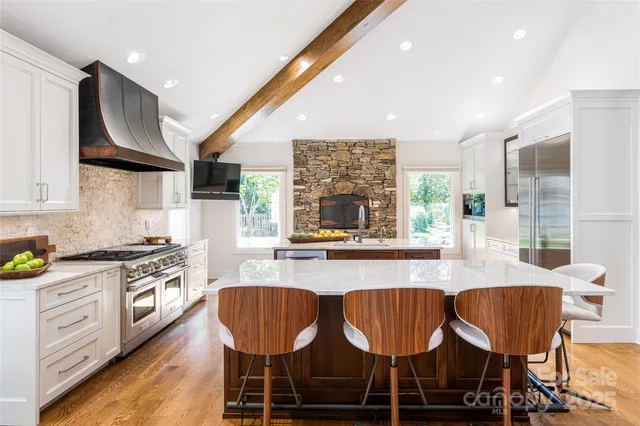 a kitchen with stainless steel appliances granite countertop a stove a sink a microwave a dining table and chairs with wooden floor