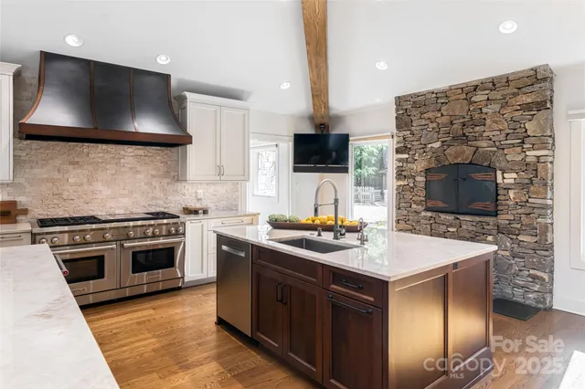 a kitchen with stainless steel appliances a stove a sink a microwave a refrigerator and a stove