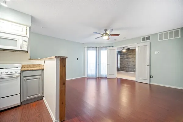 a view of a kitchen with a stove wooden cabinets and wooden floor