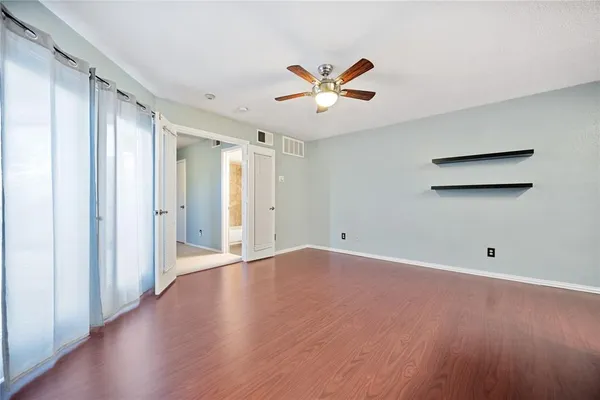 a view of an empty room with wooden floor and a window