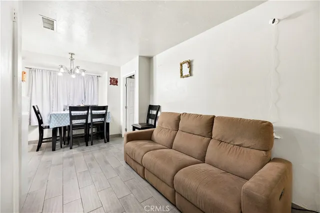 a living room with furniture a dining table with kitchen view and a potted plant
