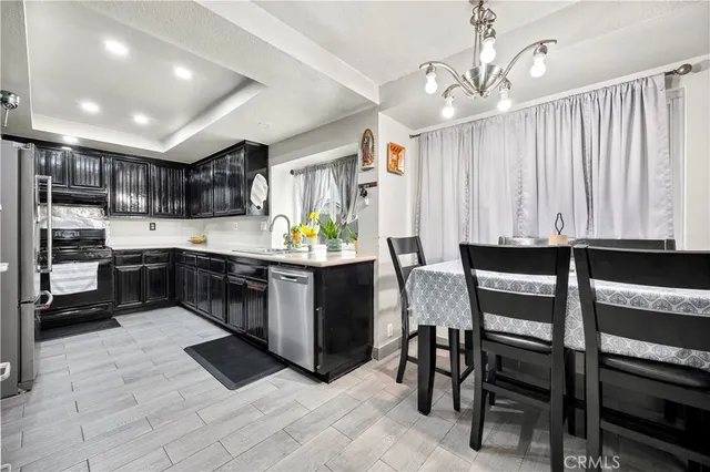 a kitchen with stainless steel appliances kitchen island granite countertop a table chairs sink and cabinets