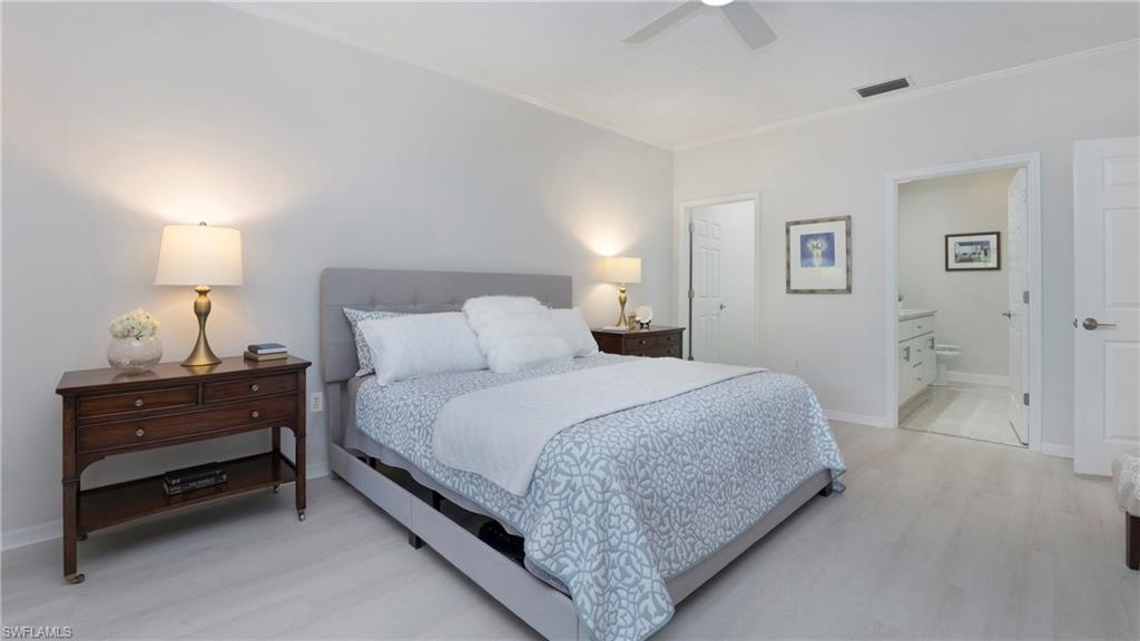 606 Arbor Lake Drive, Unit 6104 Naples, FL 34110 - Photo 13 of 36 a bedroom with a bed and a lamp on dresser