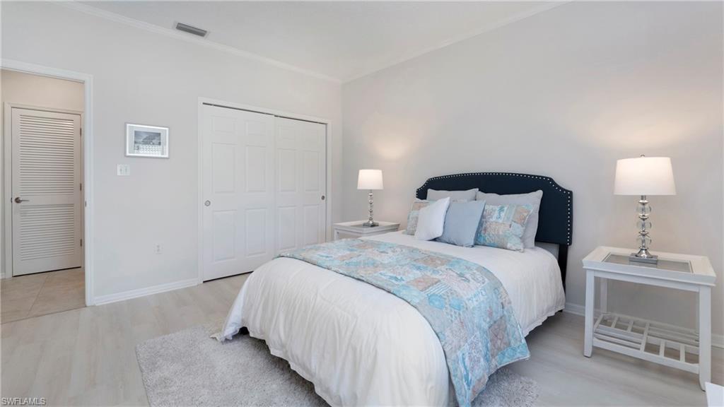 606 Arbor Lake Drive, Unit 6104 Naples, FL 34110 - Photo 17 of 36 a bedroom with a bed and a lamp