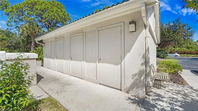 a view of a white house with a large tree and wooden fence
