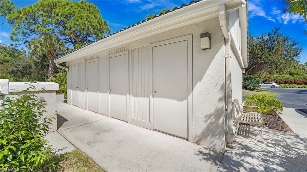 606 Arbor Lake Drive, Unit 6104 Naples, FL 34110 - Photo 22 of 36 a view of a white house with a large tree and wooden fence