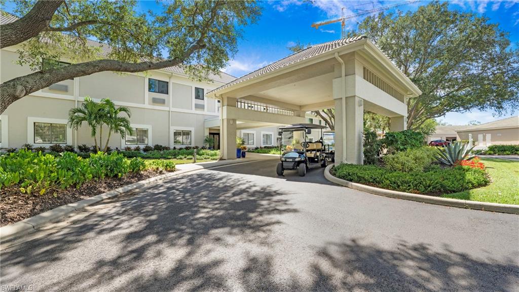 606 Arbor Lake Drive, Unit 6104 Naples, FL 34110 - Photo 28 of 36 a view of a white house with potted plants and a large tree