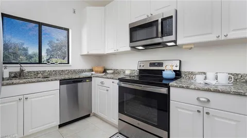 a kitchen with stainless steel appliances granite countertop white cabinets granite counter tops and a wooden floors