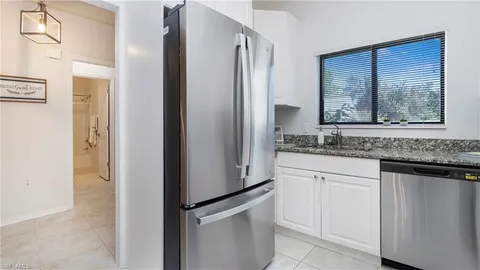 a sink with granite countertop cabinets and window