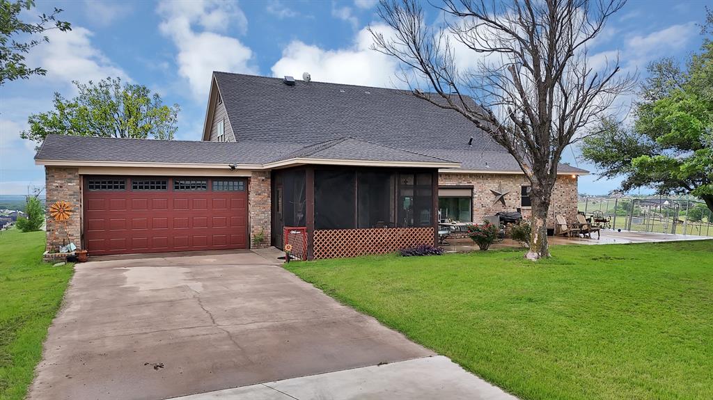 100 Shadle Ridge Court Poolville, TX 76487 - Photo 24 of 40 Brick exterior featuring a screened porch, a paved driveway, and an attached garage with a red door