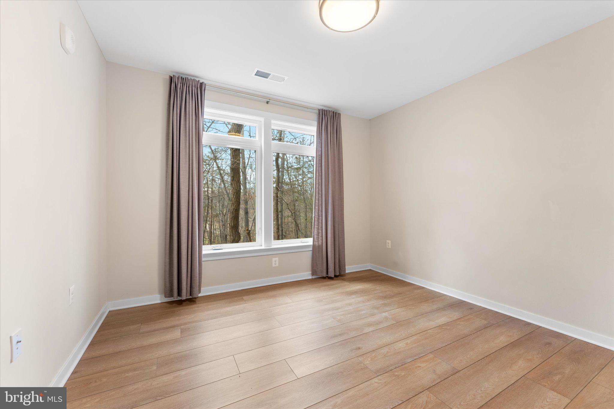 1669 Bandit Loop, Unit 206A Reston, VA 20190 - Photo 13 of 60 a view of an empty room with wooden floor and a window