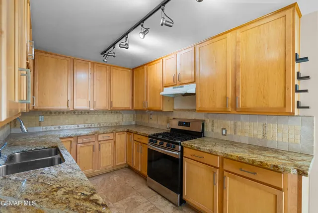 a kitchen with stainless steel appliances granite countertop a sink a stove and a refrigerator