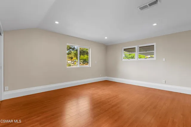 an empty room with wooden floor and window