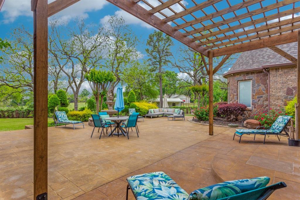 7212 John McCain Road Colleyville, TX 76034 - Photo 26 of 36 a view of a patio with a table and chairs under an umbrella with a fire pit