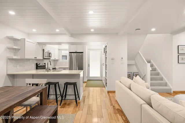 a living room with stainless steel appliances kitchen island granite countertop furniture and a wooden floor
