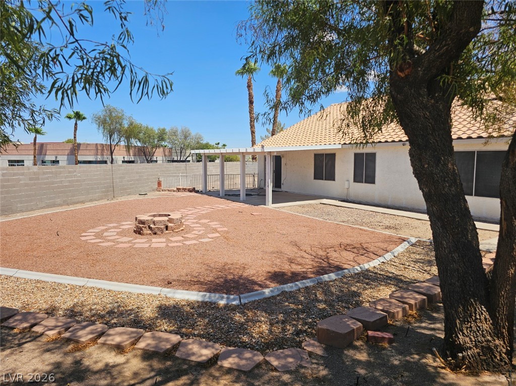 1418 Reebok Terrace Henderson, NV 89014 - Photo 36 of 38 A spacious desert-scaped private yard features a central fire pit and a covered patio, ideal for outdoor gatherings.