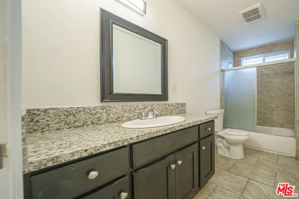 a bathroom with a granite countertop sink a toilet and a mirror