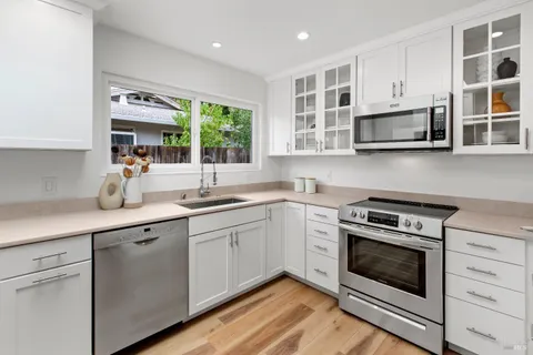a kitchen with cabinets stainless steel appliances and a window