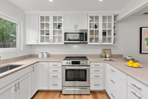 a kitchen with white cabinets and window