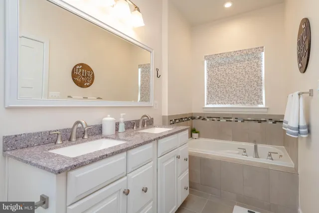 a bathroom with a granite countertop sink and a bathtub