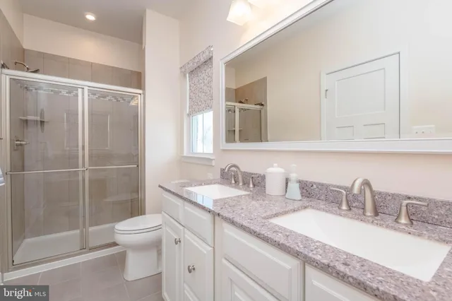 a bathroom with a granite countertop sink mirror vanity and toilet