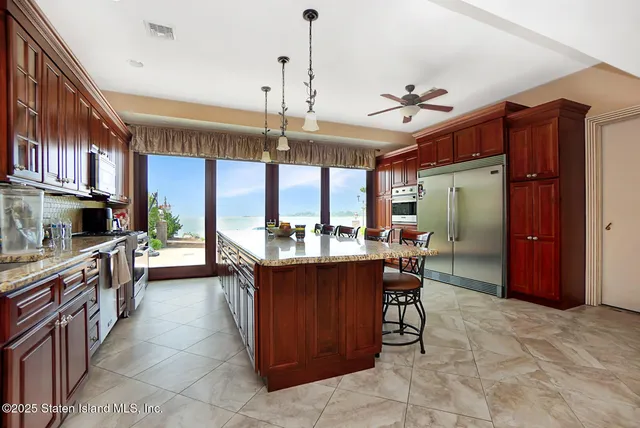 a kitchen with stainless steel appliances kitchen island granite countertop a table chairs and a refrigerator