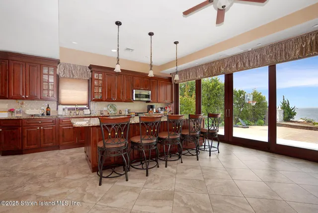 a open kitchen with stainless steel appliances granite countertop a stove top oven a sink a dining table and chairs with the wooden floor