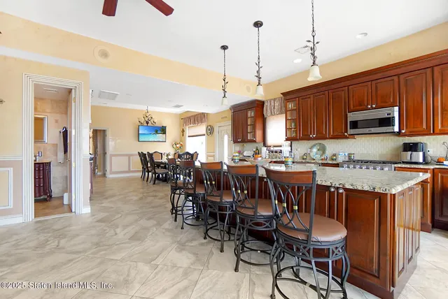 a open kitchen with stainless steel appliances granite countertop a stove top oven a sink a dining table and chairs with the wooden floor