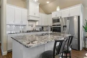 a kitchen with stainless steel appliances granite countertop a table chairs stove microwave and refrigerator