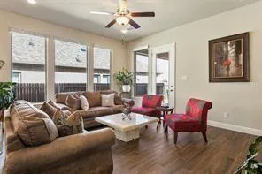 a living room with furniture two large windows and a flat screen tv