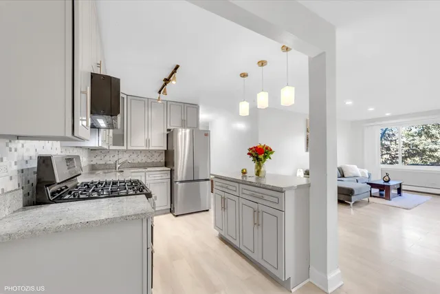 a kitchen with stainless steel appliances a stove a refrigerator a sink dishwasher and white cabinets with wooden floor