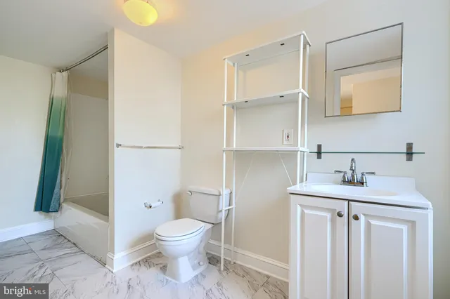 a bathroom with a granite countertop sink a toilet and a mirror
