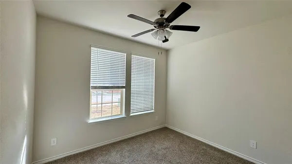 an empty room with a window and a fan