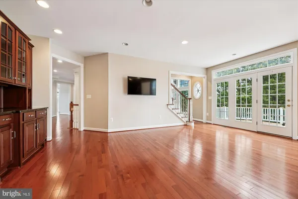 a view of an empty room with wooden floor fireplace and a window