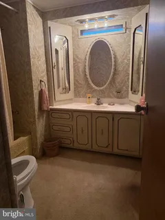 a bathroom with a granite countertop toilet sink and mirror