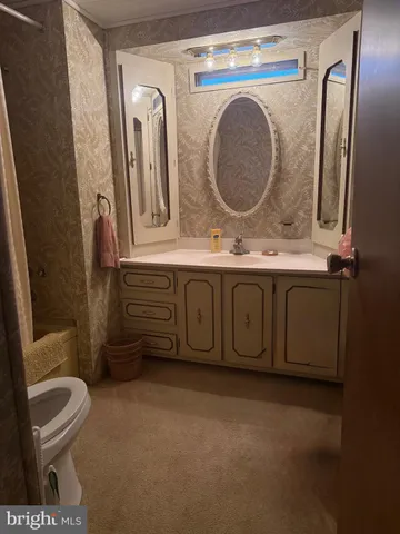 a bathroom with a granite countertop toilet sink and mirror