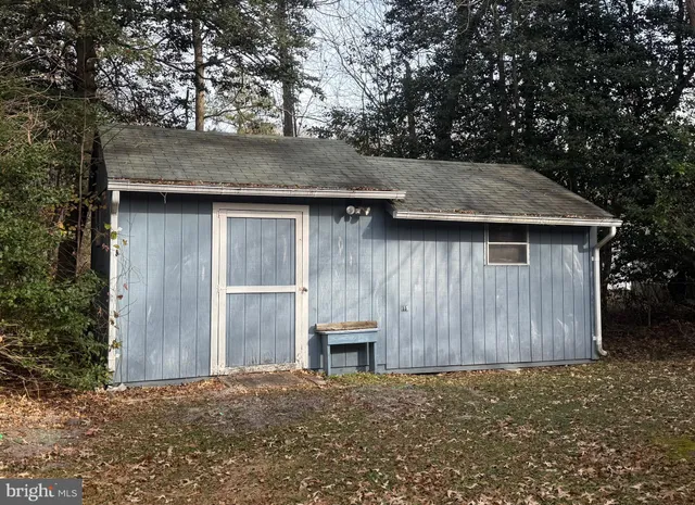 a backyard of a house with large trees and wooden fence