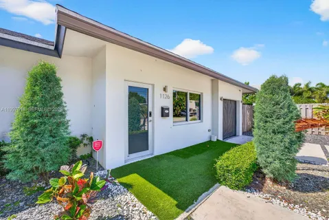 a front view of a house with a yard and potted plants