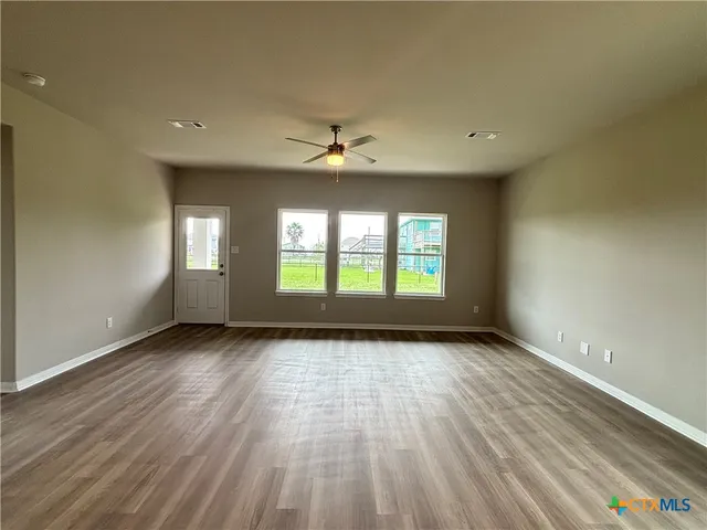 a view of an empty room with a window and wooden floor