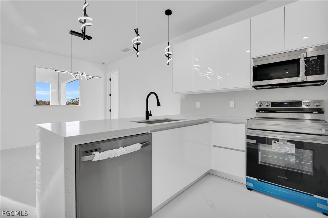 1819 Rush Avenue Lehigh Acres, FL 33972 - Photo 11 of 40 a kitchen with stainless steel appliances a stove a sink and a microwave