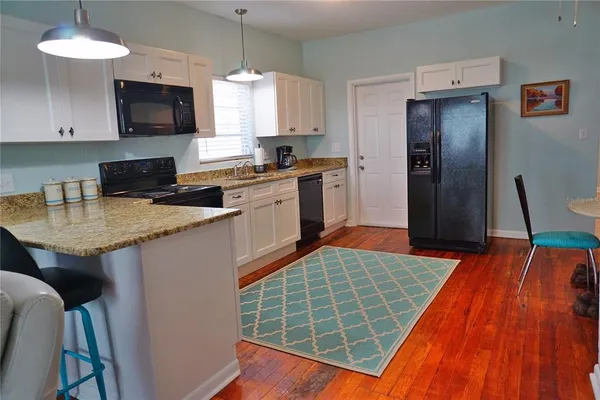 a kitchen with granite countertop wooden floors a stove a microwave a center island and stainless steel appliances