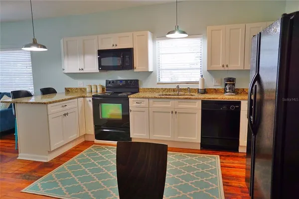 a kitchen with stainless steel appliances granite countertop a refrigerator a stove a sink and a microwave