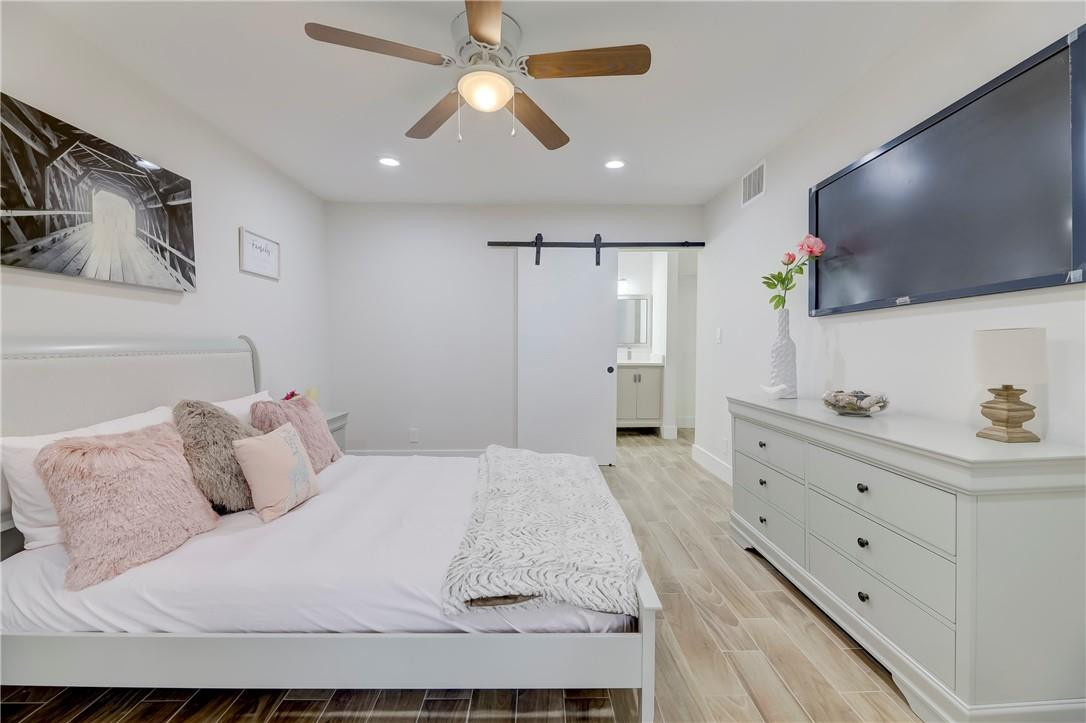 8577 Boca Glades Boulevard, Unit H Boca Raton, FL 33434 - Photo 13 of 34 a bedroom with a bed a flat screen tv and a chandelier