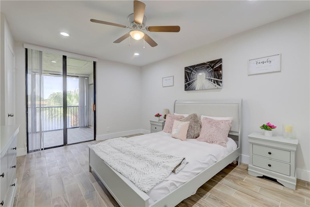 8577 Boca Glades Boulevard, Unit H Boca Raton, FL 33434 - Photo 15 of 34 a bedroom with a large bed and a chandelier