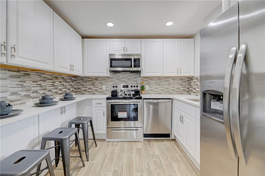 8577 Boca Glades Boulevard, Unit H Boca Raton, FL 33434 - Photo 8 of 34 a kitchen with granite countertop a refrigerator stove a sink and white cabinets