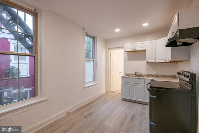 a kitchen with granite countertop a sink cabinets stainless steel appliances and a window