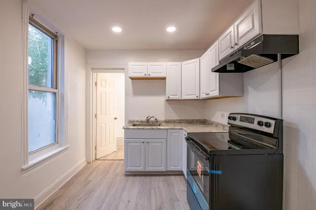 a kitchen with stainless steel appliances granite countertop a sink a stove and a wooden floors