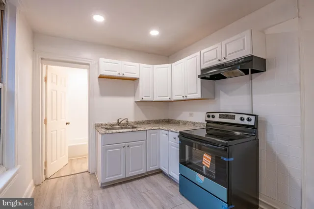 a kitchen with stainless steel appliances a stove a sink and white cabinets