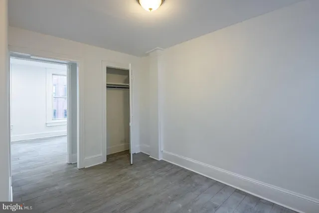 an empty room with wooden floor closet and windows