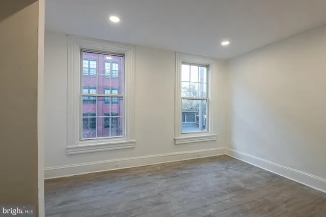an empty room with wooden floor and windows